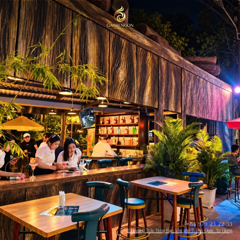 Không gian quầy bar ngoài trời Gánh Ngon với vách gỗ và cây xanh nhiệt đới
