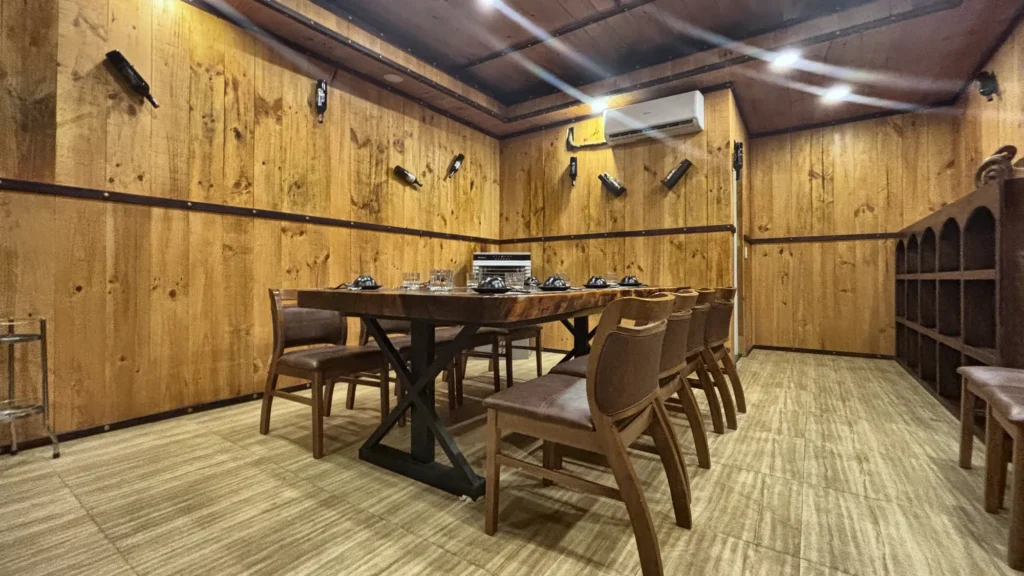 Phòng VIP 08 (Đảo Ngọc) tại Gánh Ngon: tường ốp gỗ, sàn gỗ sáng màu, bàn gỗ dài và ghế bọc nệm nâu
