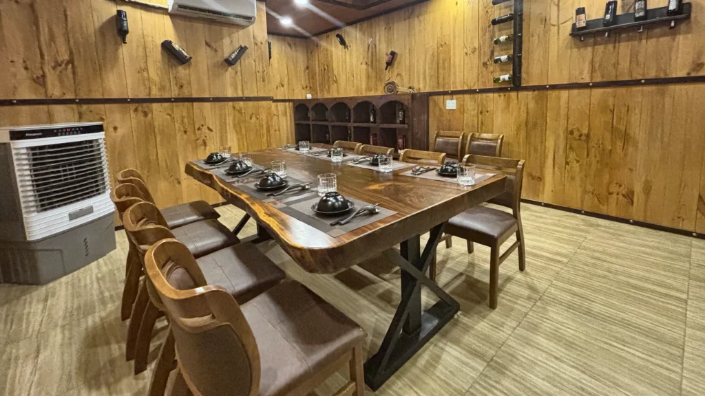 Phòng VIP 08 (Đảo Ngọc) tại Gánh Ngon: tường ốp gỗ, sàn gỗ sáng màu, bàn gỗ dài và ghế bọc nệm nâu