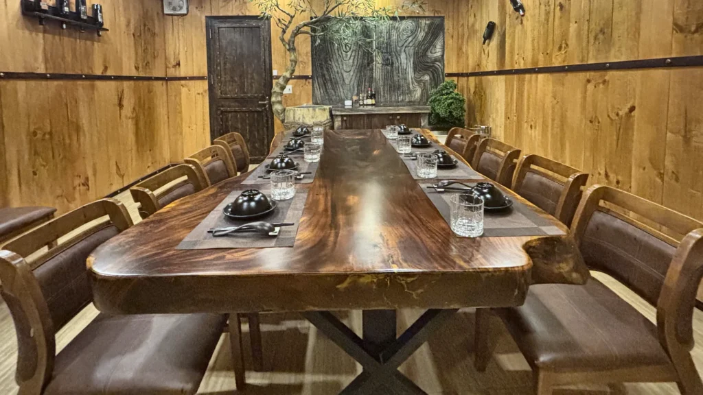 Phòng VIP 08 (Đảo Ngọc) tại Gánh Ngon: tường ốp gỗ, sàn gỗ sáng màu, bàn gỗ dài và ghế bọc nệm nâu